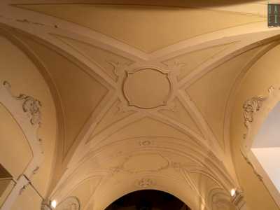 Il soffitto voltato invece mostra geometriche cornici modanate a stucco bianco